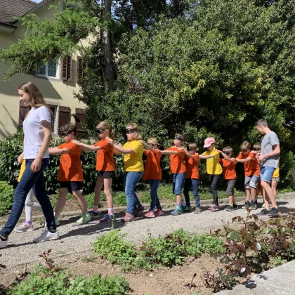 Kinder laufen in einer Kolonne durch den Garten